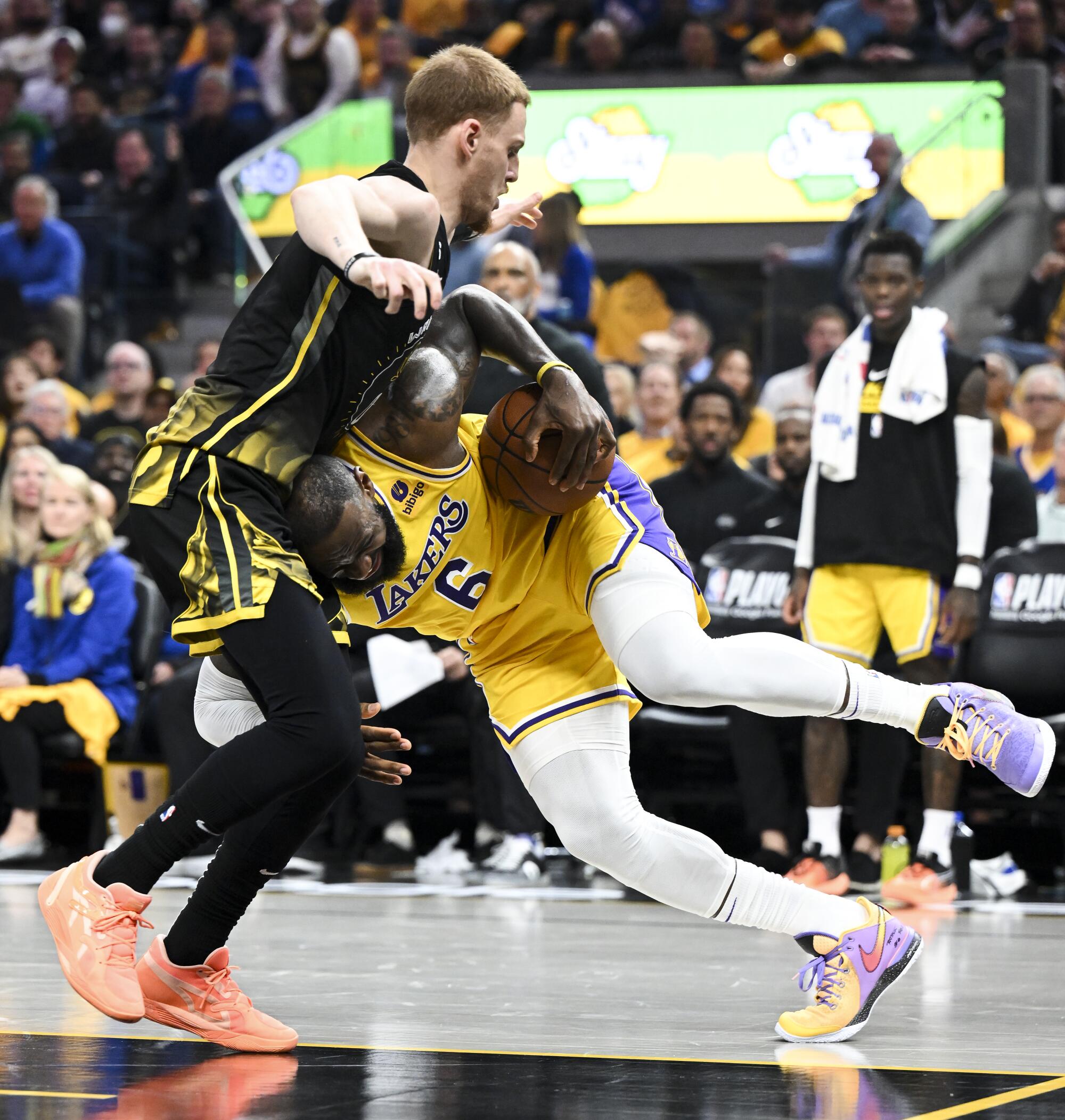 Lakers forward LeBron James, right, moves the ball against Warriors guard Donte DiVincenzo during the second quarter.