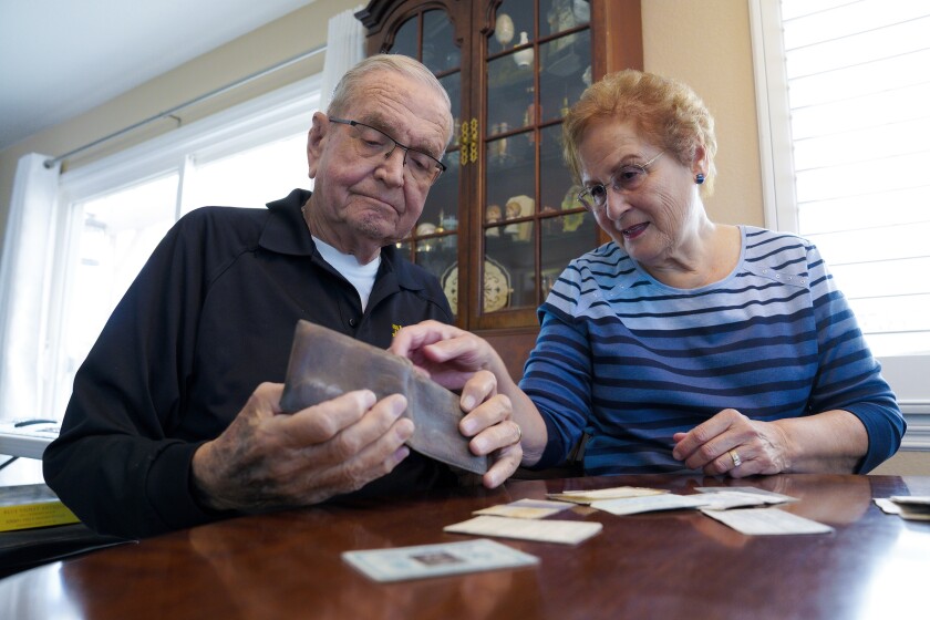 Paul Grisham and his wife Carole Salazar look over his wallet and the items that were inside when he lost the wallet back in 1968 at their home in the San Carlos section of San Diego, Calif., Wednesday, Feb. 3, 2021. Grisham’s wallet was missing for so long he forgot all about it. Fifty-three years later, the 91-year-old has the billfold back along with mementos of his 13-month assignment as a Navy meteorologist on Antarctica in the 1960s. (Nelvin C. Cepeda/The San Diego Union-Tribune via AP)