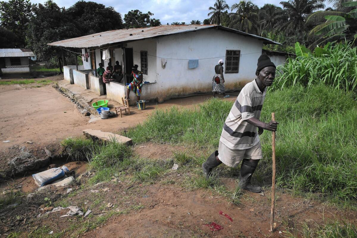 A neighbor walks past the building where Eric Duncan, the first Ebola patient to develop symptoms in the United States, rented a room in Paynesville, a neighborhood near Monrovia, Liberia.
