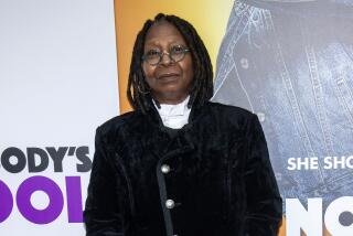 Whoopi Goldberg in a black suit poses at a red carpet event