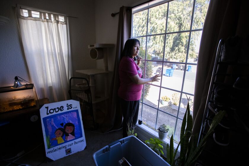 EL SERENO, CA - October 24, 2022 - Martha Escudero, 44, looks out the living room window of her home. Escudero and her two daughters are facing eviction from a state-owned home they have lived in for two years. Photographed Monday, Oct. 24, 2022 in El Sereno, CA.(Brian van der Brug / Los Angeles Times)