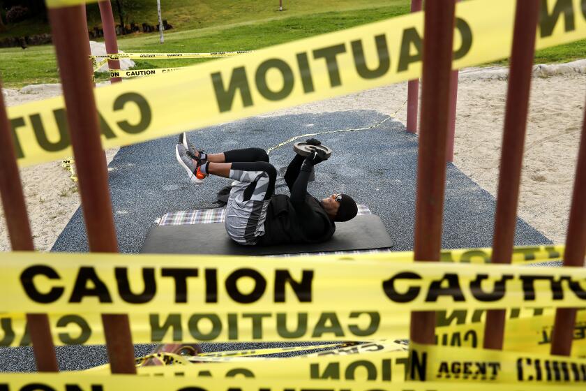 TORRANCE-CA-APRIL 2, 2020: Robert Hennie, 51, an independent filmmaker, sets up a makeshift gym in the children's playground, where caution tape prevents kids from playing, to slow the spread of the coronavirus, at De Portola Park in Torrance on Thursday, April 2, 2020. Californians are finding ways to work out due to gym closures amid the Coronavirus. (Christina House / Los Angeles Times)