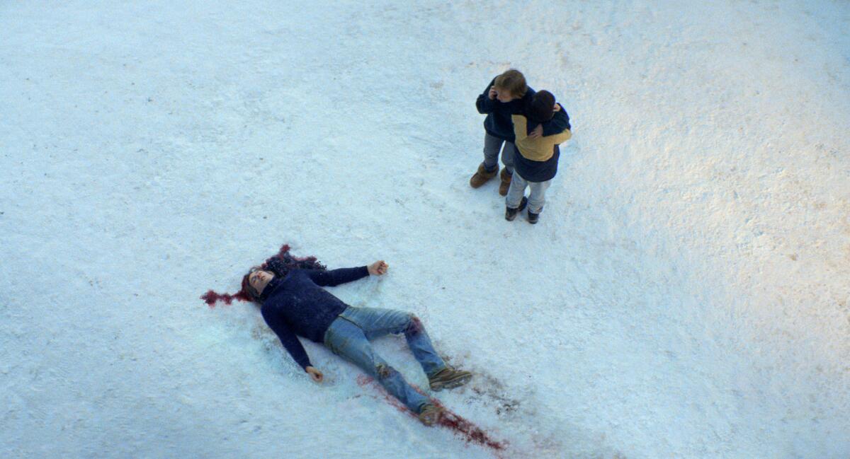 A boy and a woman look over a man's corpse on the snow.