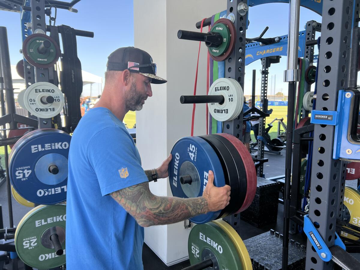 Nick Hardwick, who is helping to teach the Chargers offensive linemen, adds weights to a lift bar.