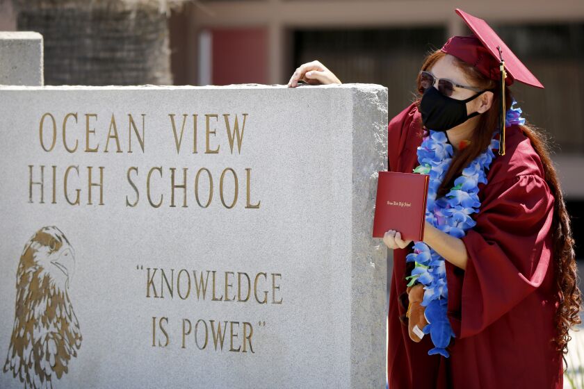 Angelyte Pantoja, 18 of Santa Ana, poses for some family photos after getting her diploma during a drive-thru graduation at Ocean View High School, in Huntington Beach on Wednesday, June 10, 2020. More than 280 students drove through the school during the day at a pace of about 50 an hour.