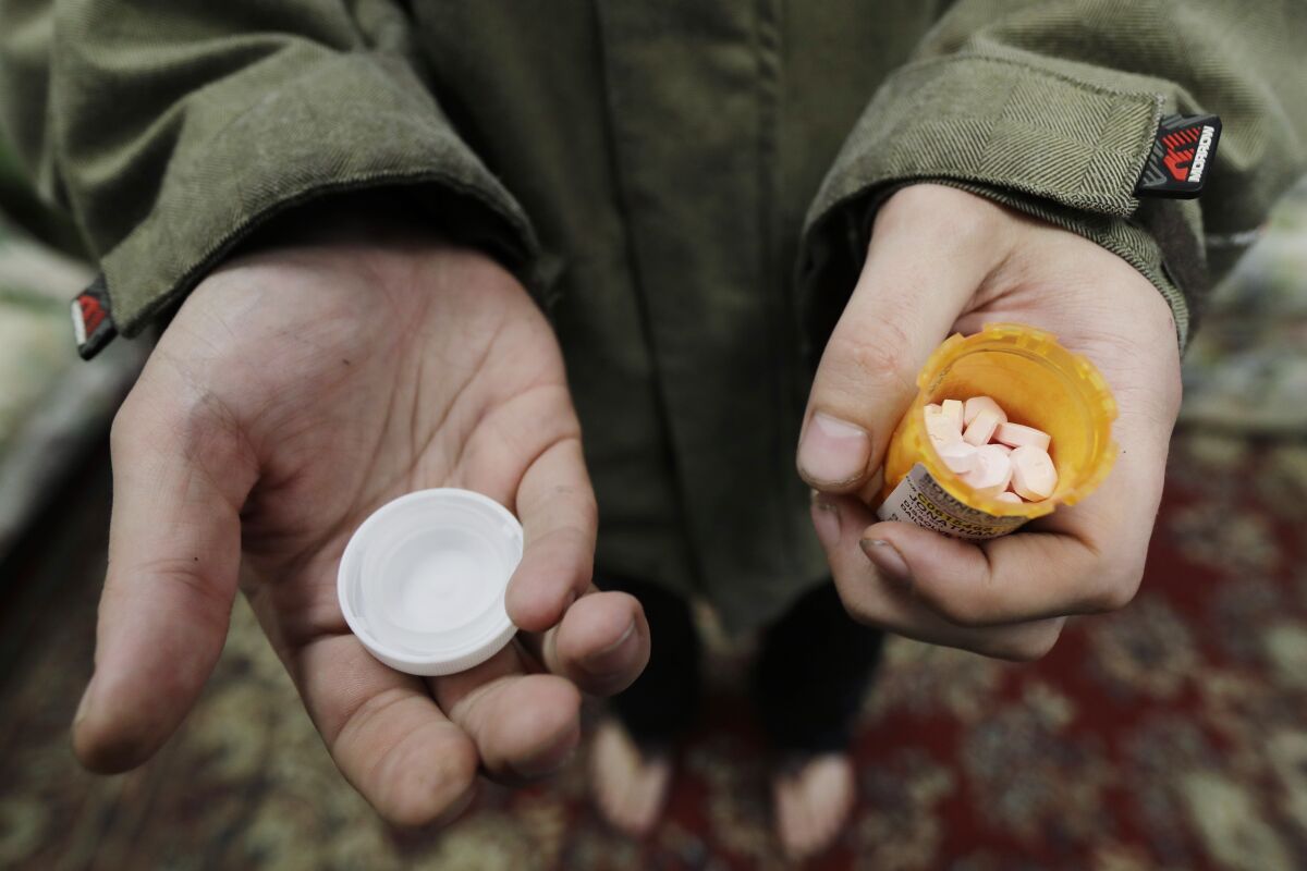 FILE - In this Nov. 14, 2019, photo, Jon Combes holds his bottle of buprenorphine, a medicine that prevents withdrawal sickness in people trying to stop using opiates, as he prepares to take a dose in a clinic in Olympia, Wash. The U.S. Department of Justice made clear, Tuesday, April 2, 2022, that barring the use of medication treatment for opioid abuse is a violation of federal law. (AP Photo/Ted S. Warren, File)