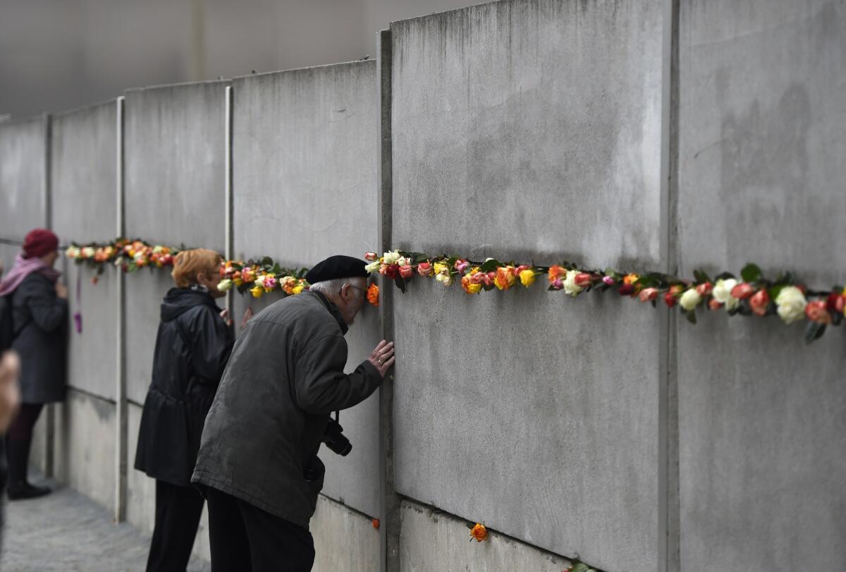 Visitors look through a preserved segment of the Berlin Wall decorated with roses during commemorations to mark the 25th anniversary of its fall at the Berlin Wall Memorial on Nov. 9.