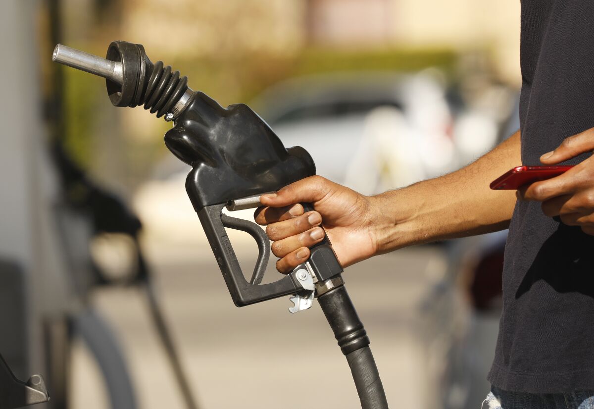 A person holds the handle of a fuel pump at a gas station. 