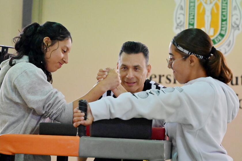 Jocelyn Camacho (left) and Yosselin Flores both competed in the women's division of the sports club, "War of Arms" first two-day inaugural municipal arm wrestling tournament at the Autonomous University of Baja California (UABC) campus in Tijuana. With competitions for male and females, most participants on Friday were beginnings and eager to learn the sport of arm wrestling endorsed by the World Arm Wrestling Federation and the North American Arm Wrestling Federation in Mexico. (Carlos Moreno / The San Diego Union-Tribune)
