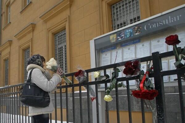A woman places a flower tribute to Houston in a fence surrounding the U.S. Embassy in Moscow.