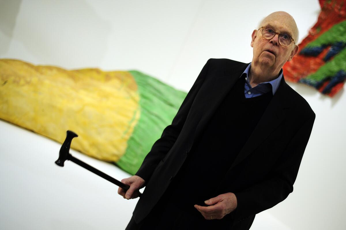 An older man in a dark suit at an art exhibition.