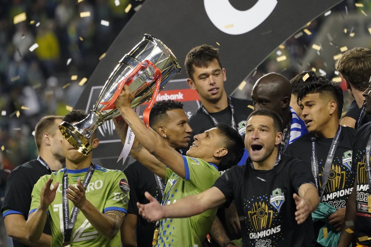 United States' Seattle Sounders forward Raul Ruidiaz holds the trophy alongside teammate midfielder Nicolás Lodeiro after the Sounders defeated Mexico's Pumas to win the CONCACAF Champions League soccer final Wednesday, May 4, 2022, in Seattle. (AP Photo/Ted S. Warren)