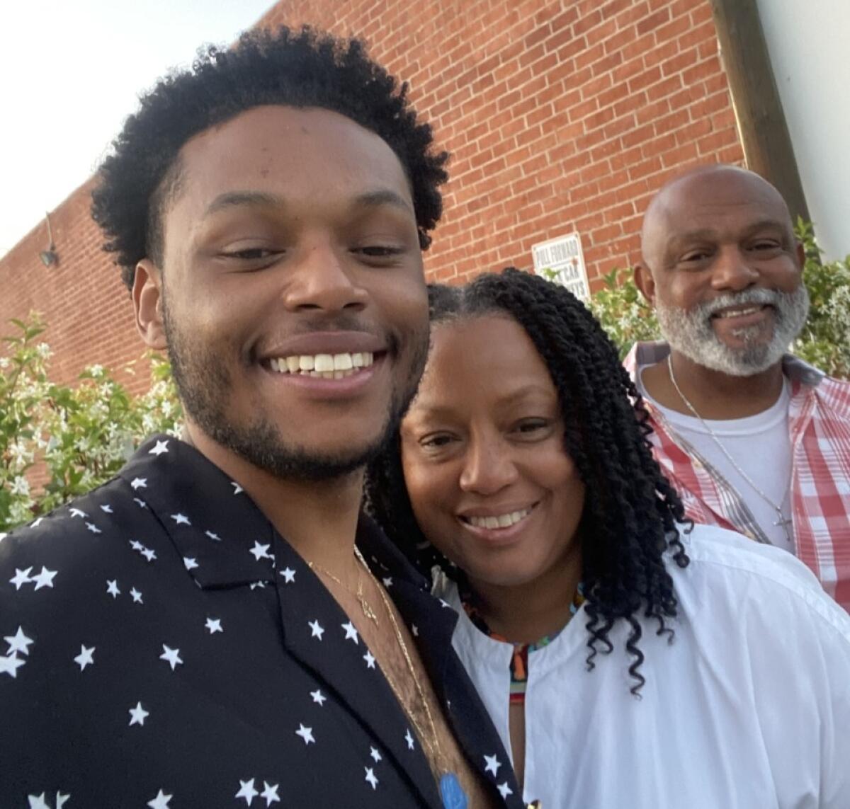 Miles stands next to his mother Valencia while his father Rodney Foster smiles in the background