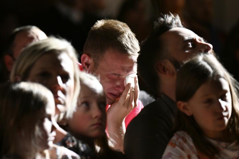 R.J. Lewis, center, attends a vigil at All Souls Unitarian Church with others, Sunday, Nov. 20, 2022, in Colorado Springs, Colo., following a fatal shooting at gay nightclub Club Q late the night before. Lewis was at Club Q when a 22-year-old gunman entered the LGBTQ nightclub killing several people and injuring multiple others. (RJ Sangosti/The Denver Post via AP)