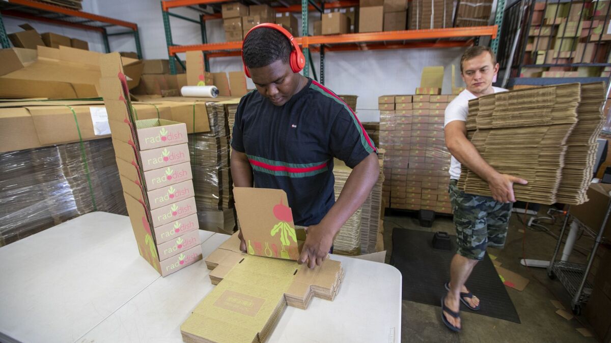 Workers Raymond Lucas, left, and Artem Lagutin fold and stack boxes ready to be filled with cooking kits at Raddish in Redondo Beach.