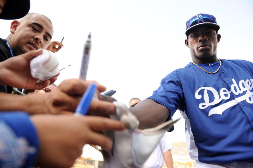 Dodgers right fielder Yasiel Puig gives away his batting glove to a fan before a game with the Braves at Dodger Stadium.