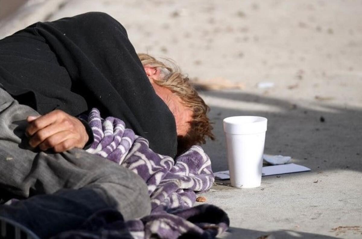 A homeless man sleeps on Placentia Avenue in Costa Mesa in January 2019.
