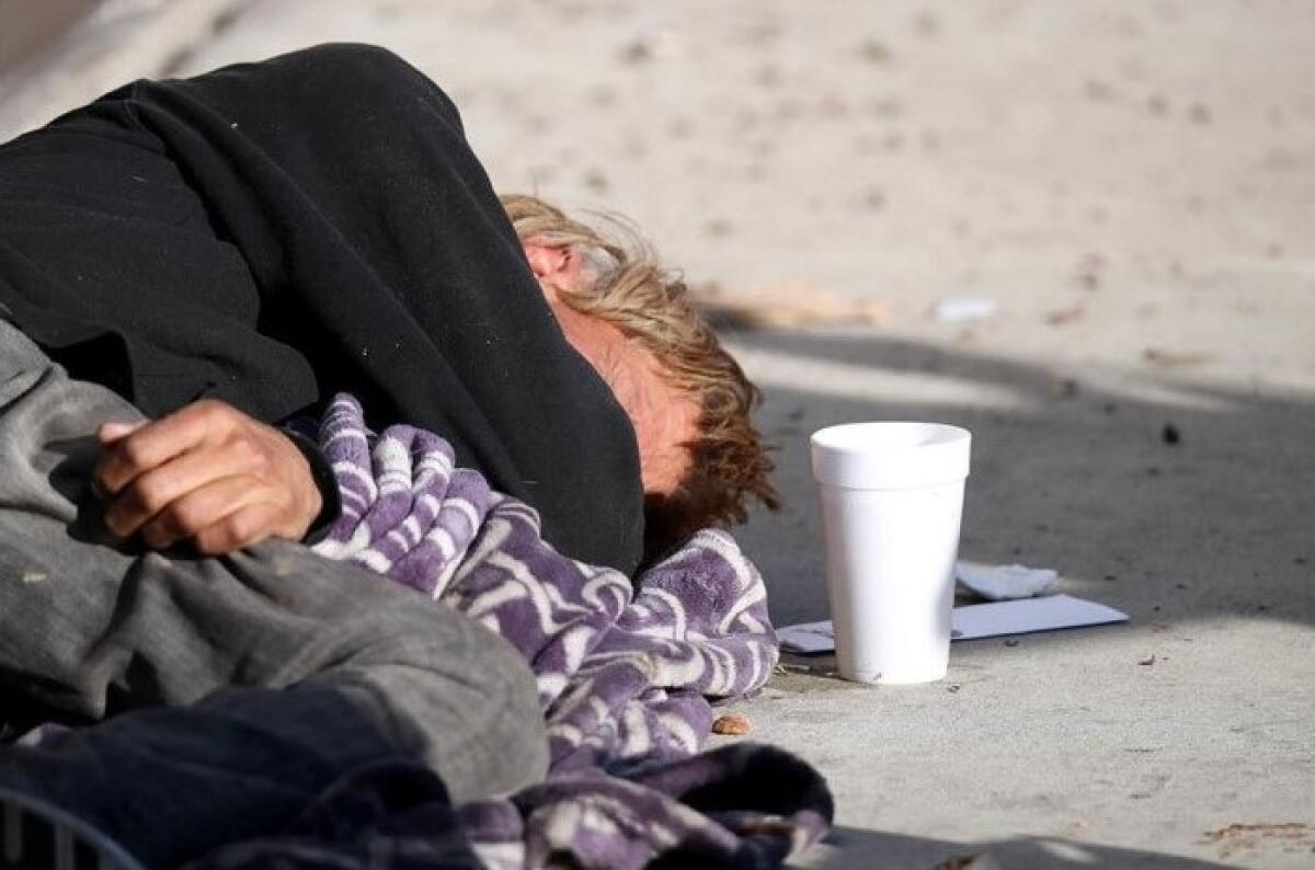 A homeless man sleeps on Placentia Avenue in Costa Mesa in this Daily Pilot file photo.
