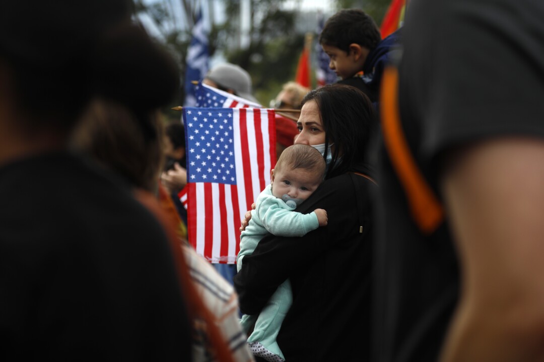 A woman holds a baby amidst a crowd of people
