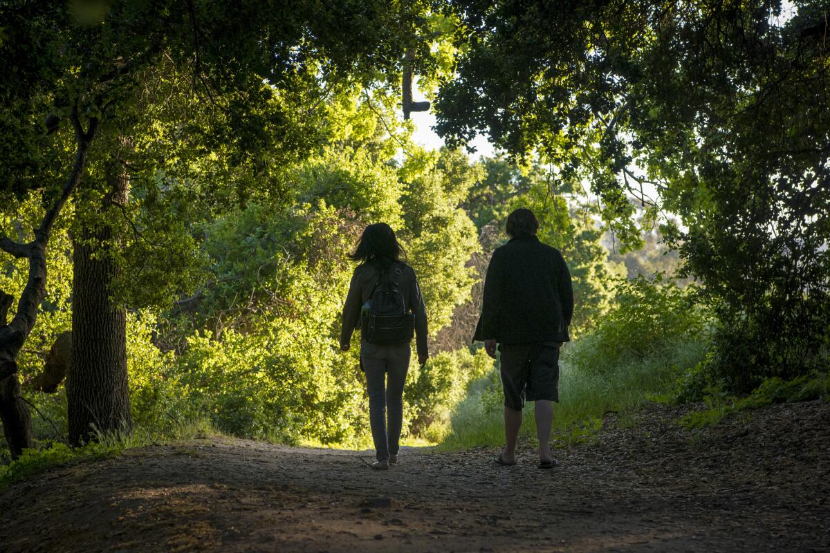 A couple hike in an oak grove.