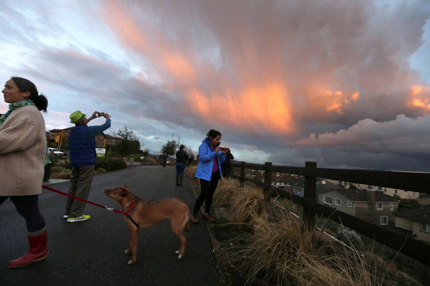Azusa residents pause to take photos of the sunset minutes after a storm front moved past Sierra Madre Ave.