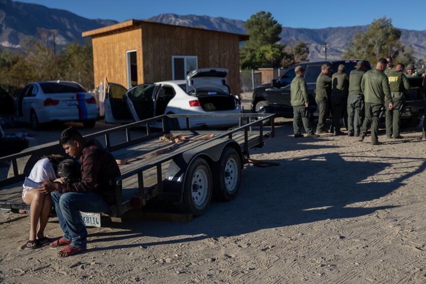 LUCERNE VALLEY, CA - September 30, 2022: Two cannabis workers comfort each other after San Bernardino sheriff's deputies served a search warrant on an illicit farm and destroyed plants Friday, Sept. 30, 2022 in Lucerne Valley, CA. (Brian van der Brug / Los Angeles Times)