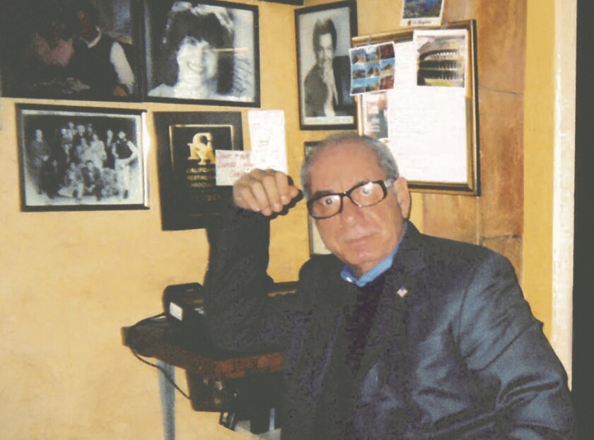 Steve Restivo by a wall of framed headshots at his restaurant, Vitello's