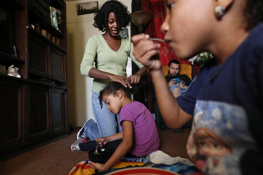 Monique Baker arranges the hair of her youngest child, Anicia, 4, during a visit before the children return to their court-ordered placement at their grandfather's home.