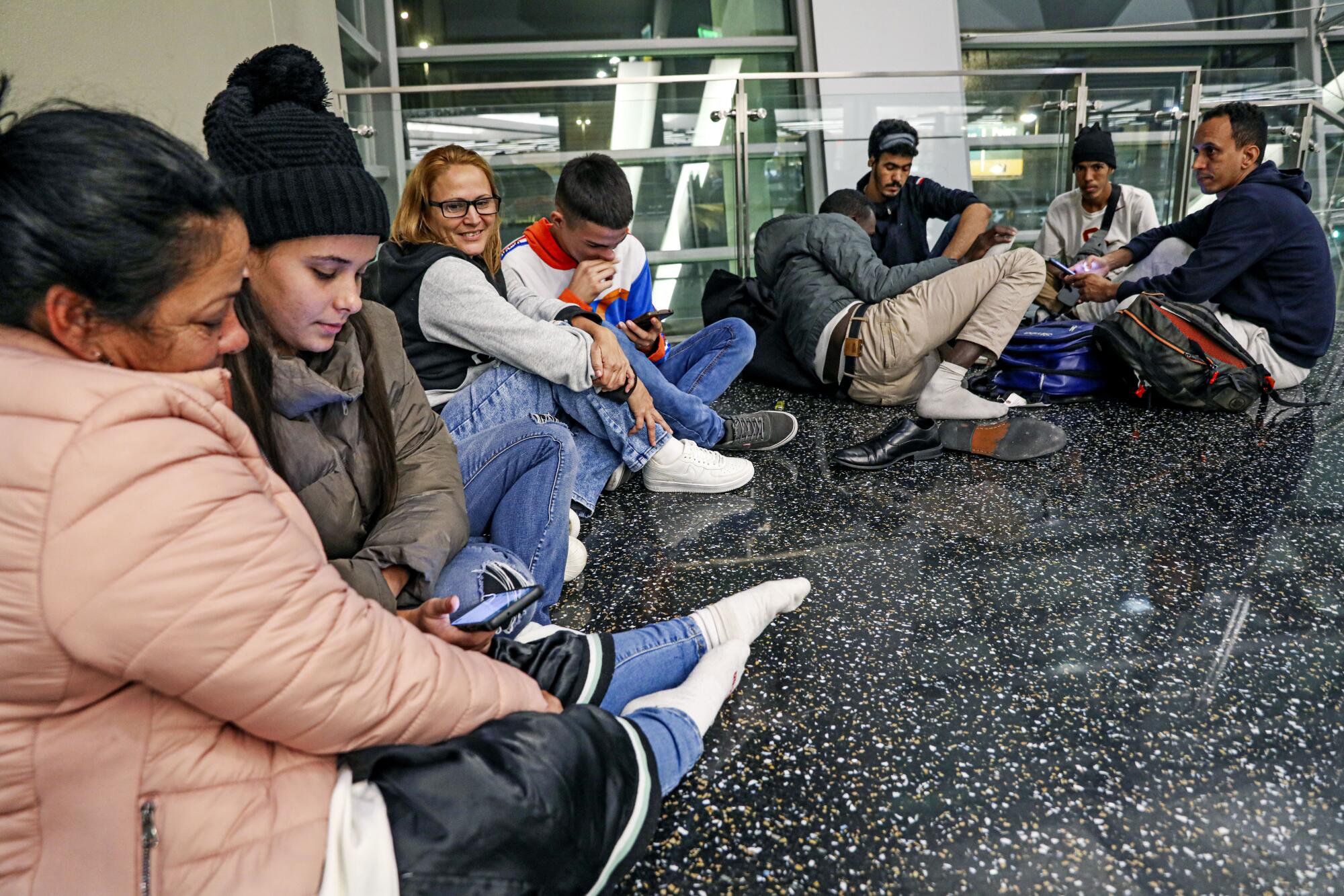 The Benavedes family from Venezuela tries to get comfortable as they wait for flights on the floor.