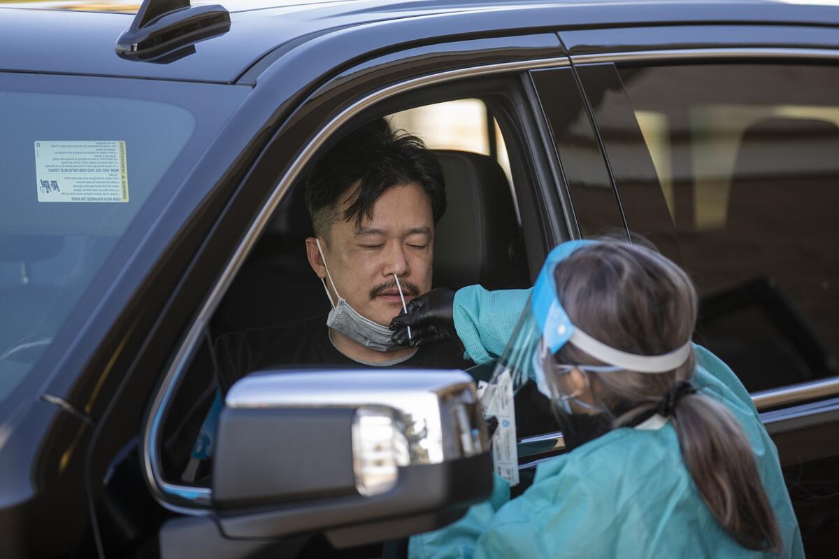 Camilla Morales administers a COVID-19 test to Thand Trinh at the Covid Clinic at the Westminster Mall on Tuesday, Jan. 4.