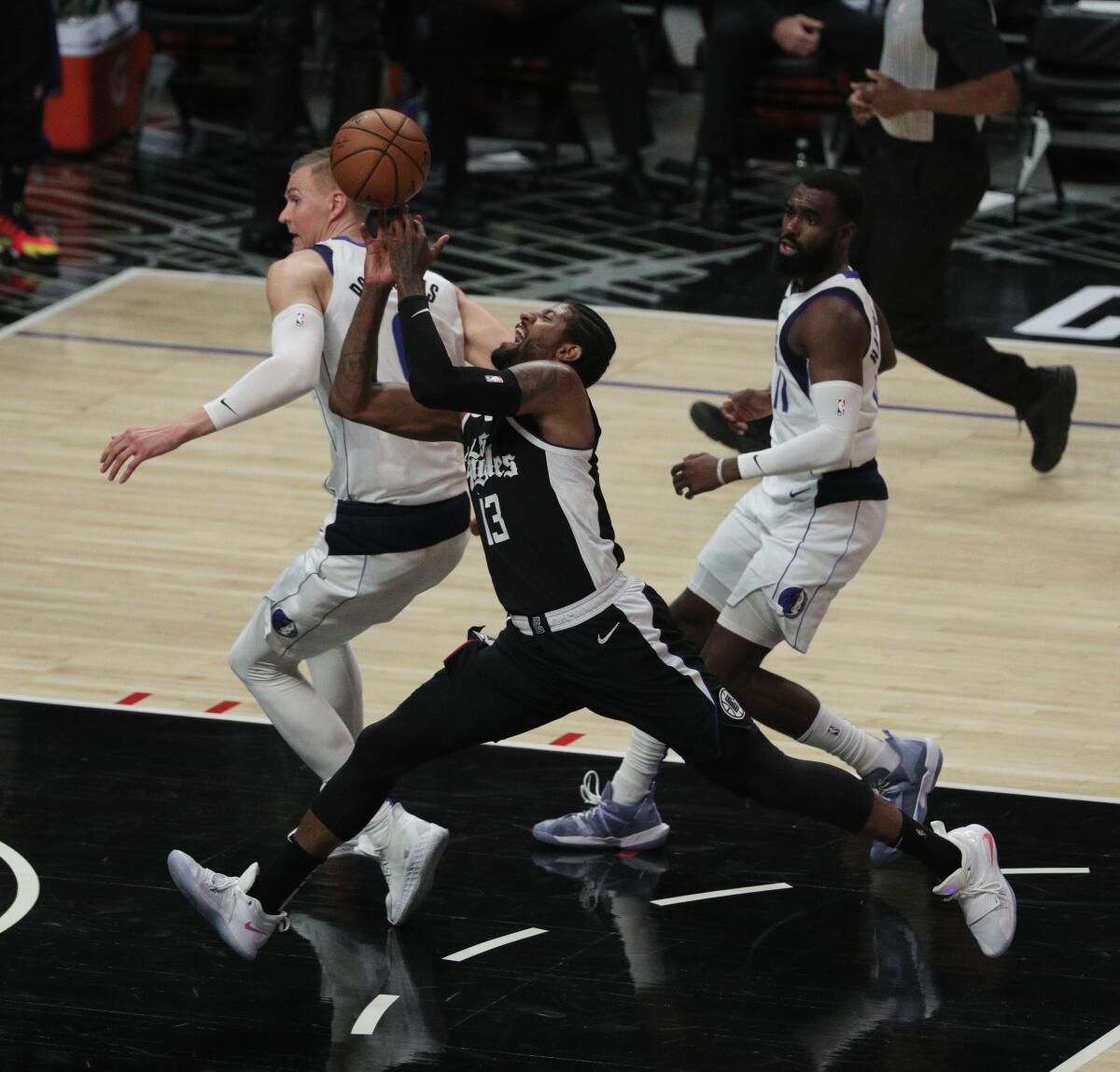 Clippers guard Paul George is fouled by Dallas Mavericks center Kristaps Porzingis.