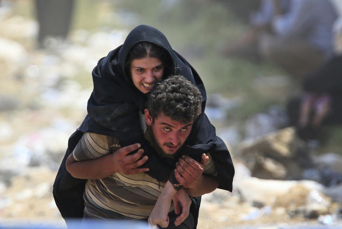 A Syrian refugee carries a sick woman on his back in Akcakale, as they flee intense fighting in northern Syria between Kurdish fighters and Islamic State militants.