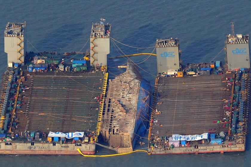The sunken ferry Sewol is raised to the surface between two barges in waters off Jindo, South Korea, on March 23, 2017.