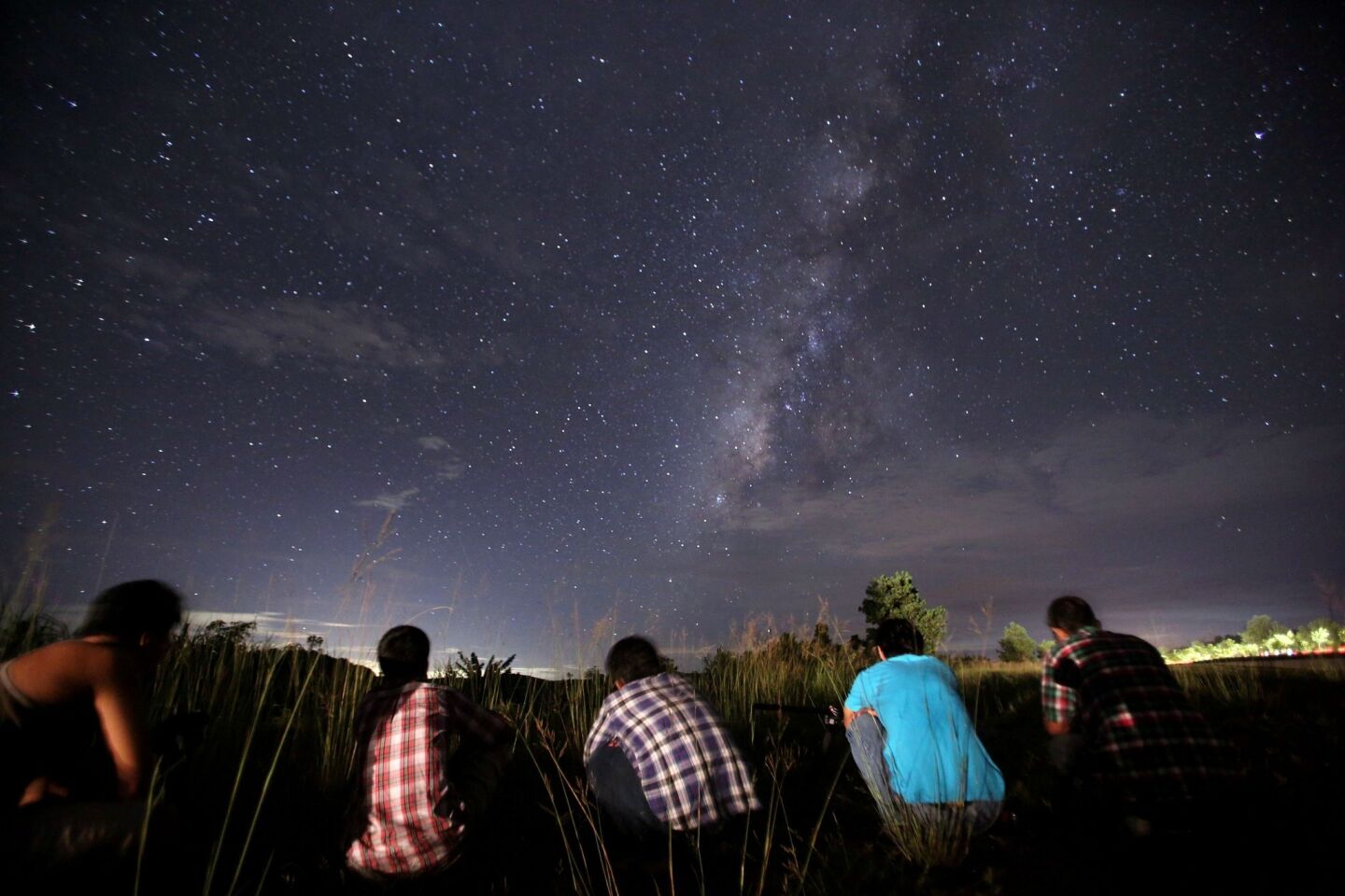 A time-exposure photograph of people watching for the Perseid meteor shower in the night sky near Yangon.