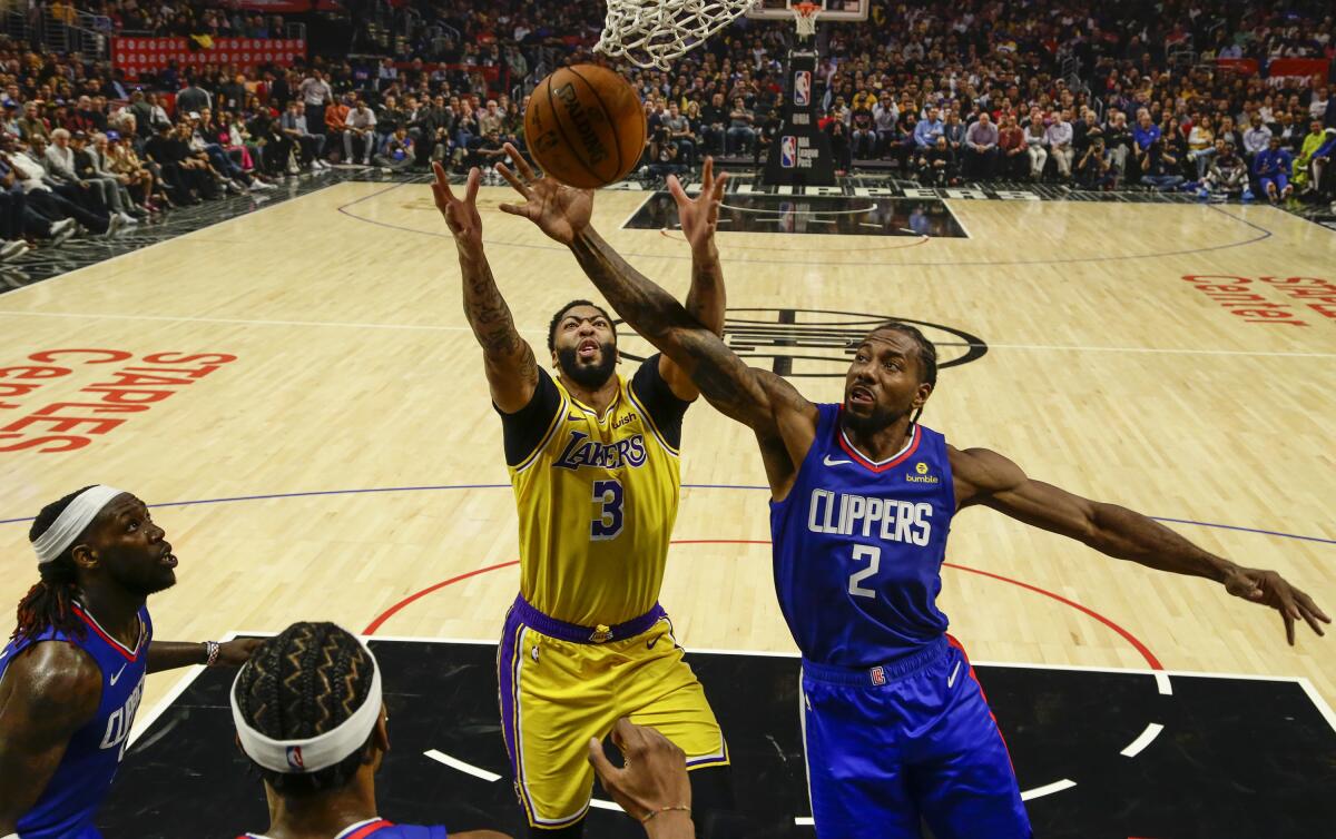 Lakers forward Anthony Davis (3) and Clippers forward Kawhi Leonard (2) battle for a rebound during the season-opening game Tuesday.