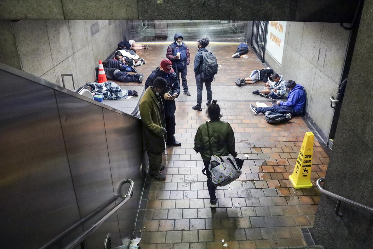 Outreach workers check on homeless people sleeping on the floor of a Metro station.
