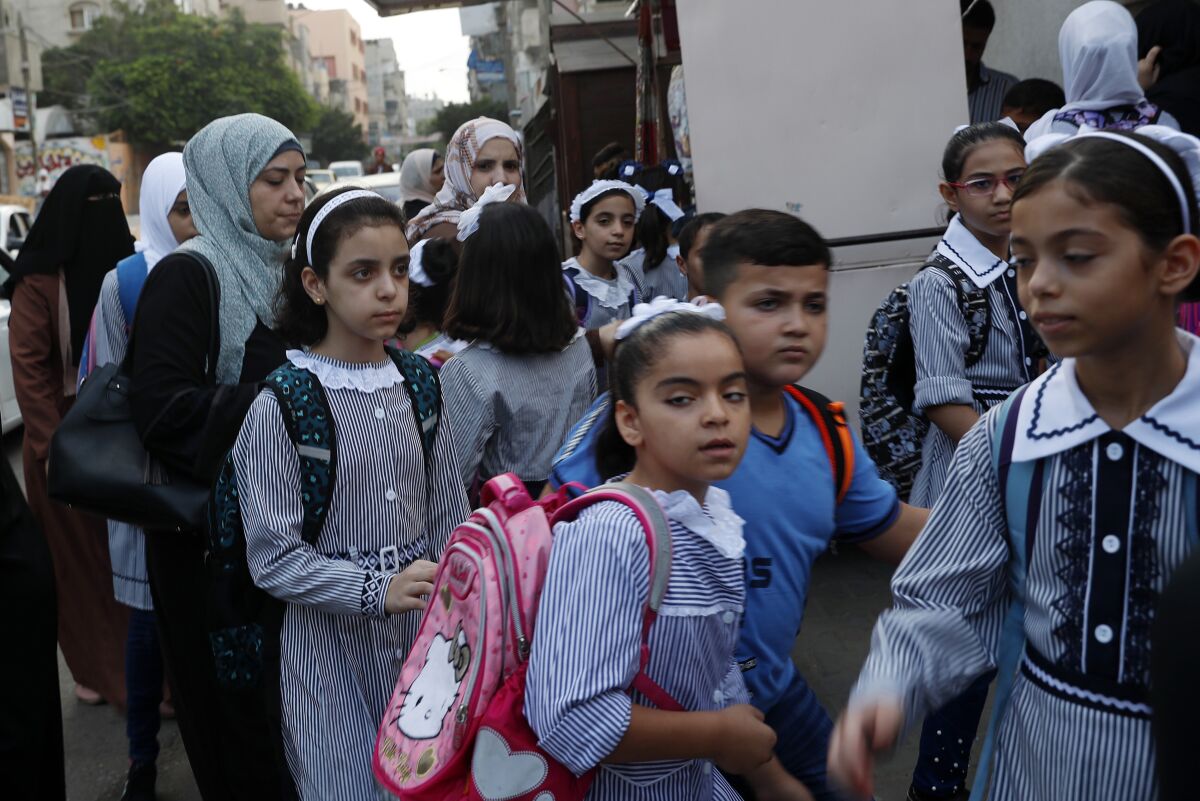Women bring their children to the United-Nation run Elementary School on the first day of the new school year at the United-Nation run Elementary School at the Shati refugee camp in Gaza City, Saturday, Aug. 8, 2020. Schools run by both Palestinian government and the U.N. Refugee and Works Agency (UNRWA) have opened almost normally in the Gaza Strip after five months in which no cases of community transmission of the coronavirus had been recorded. (AP Photo/Adel Hana)