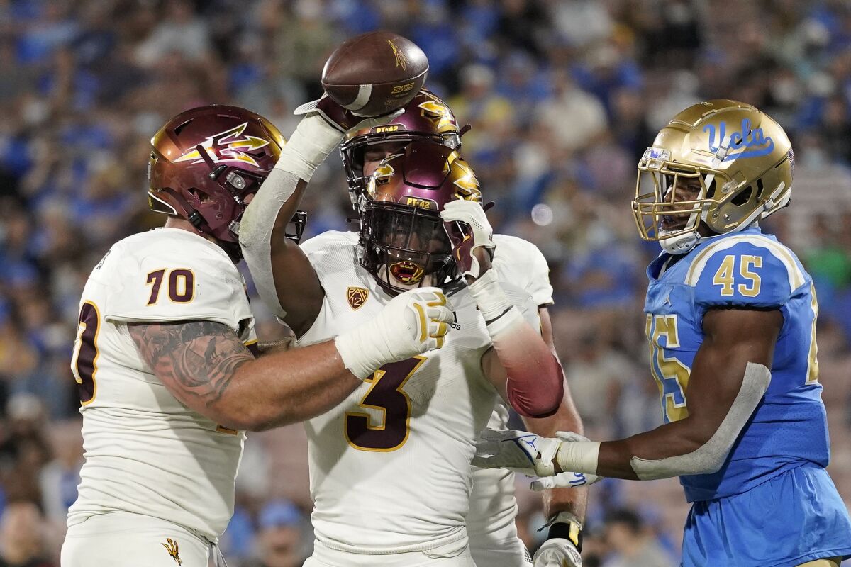 Arizona State running back Rachaad White, center, celebrates a touchdown along with offensive lineman Henry Hattis, left, as UCLA linebacker Mitchell Agude stands by during the second half of an NCAA college football game Saturday, Oct. 2, 2021, in Pasadena, Calif. Arizona State won 42-23. (AP Photo/Mark J. Terrill)