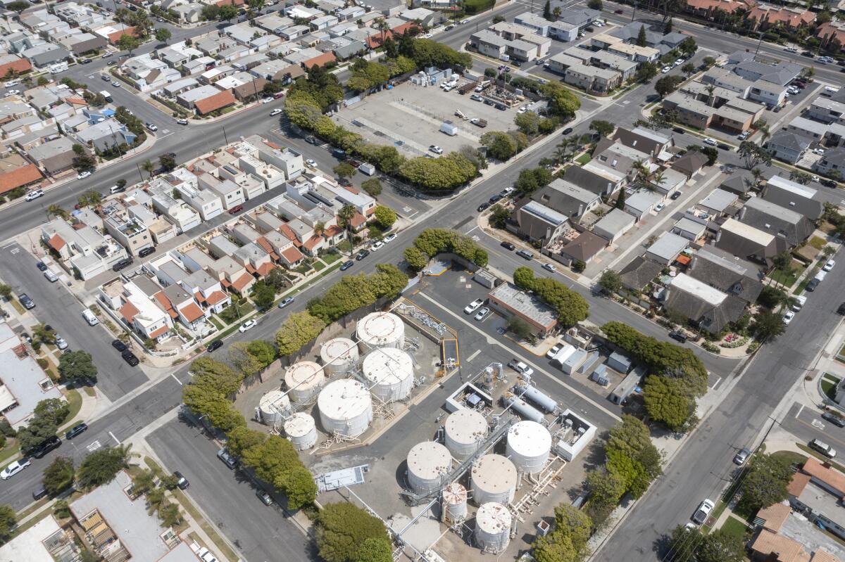 An aerial image of a group of oil storage tanks surrounded by residential homes.