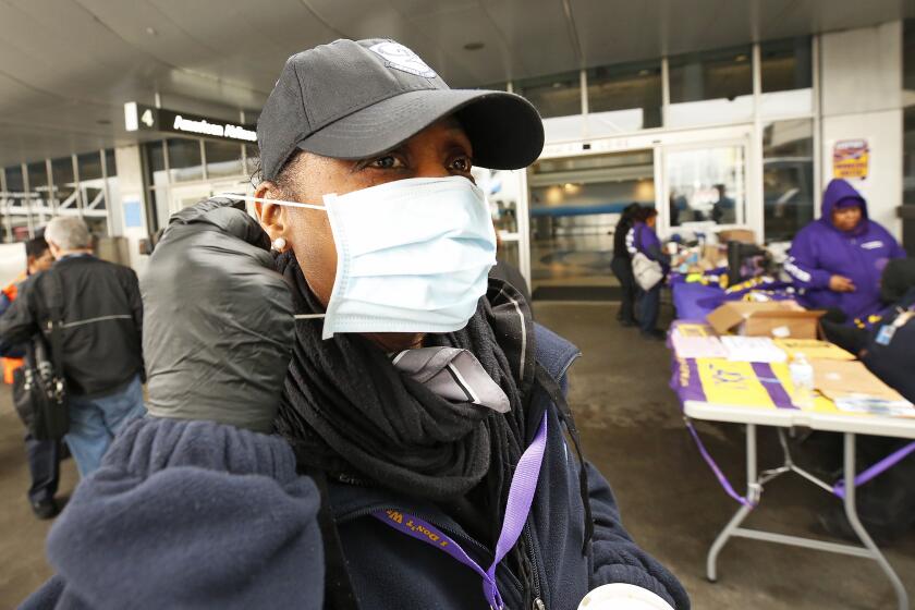 LOS ANGELES, CA - MARCH 10, 2020 Lita Godfrey, who works in customer service at Los Angeles Airport LAX wears her protective mask as she joined LAX workers who held a news conference to discuss concerns that they have been given "inadequate training and equipment for the first several weeks of coronavirus spread.'' The workers were distributing their own protective equipment to other workers throughout the day.(Al Seib / Los Angeles Times)