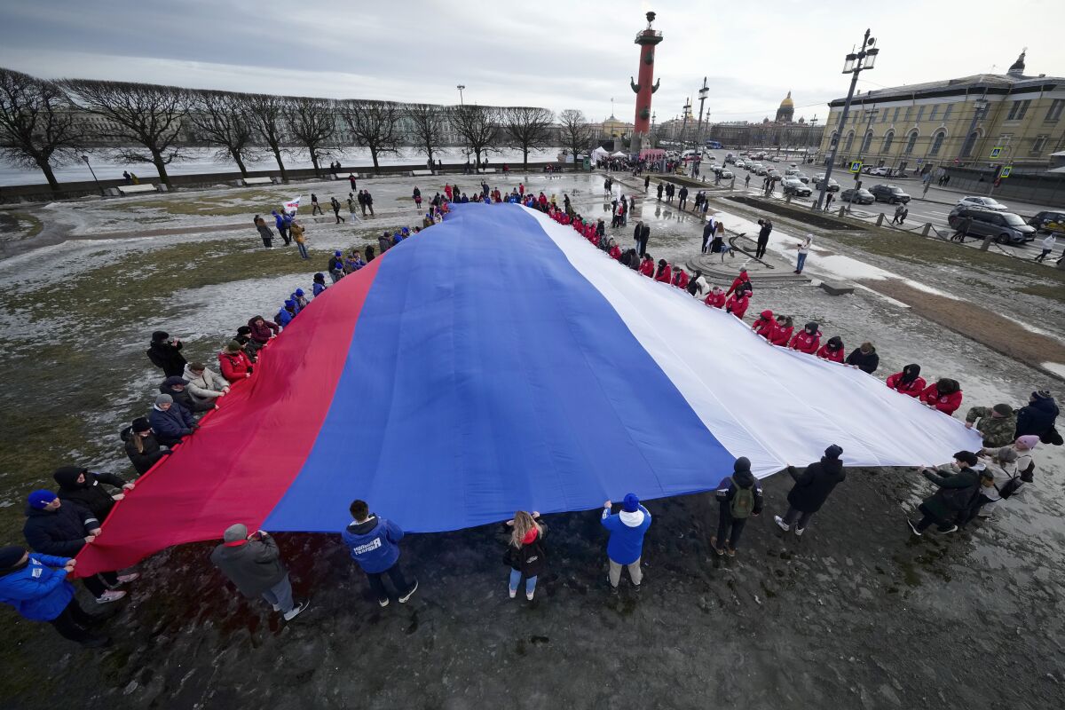 Young people unfurl a giant Russian flag during an action to mark the ninth anniversary of the Crimea annexation from Ukraine