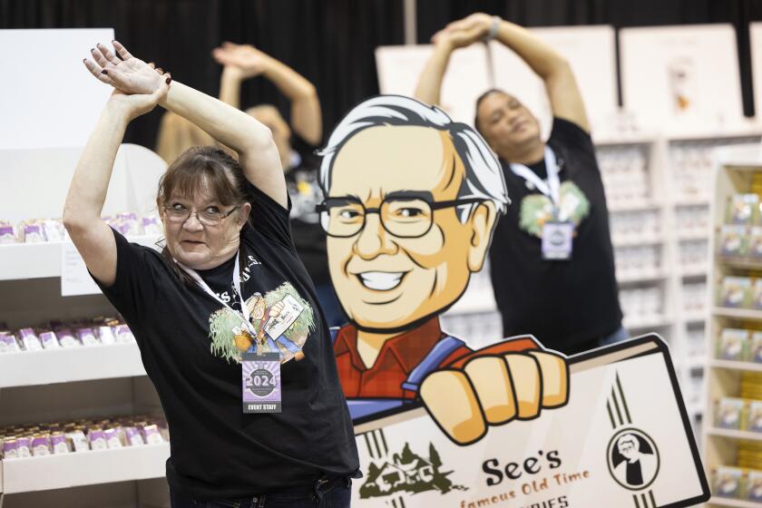 FILE - Michelle King of San Francisco does yoga in the See's Candies booth before the arrival of shareholders for the Berkshire Hathaway annual meeting on May 4, 2024, in Omaha, Neb. Berkshire Hathaway reports earnings on Saturday, Aug. 3, 2024. (AP Photo/Rebecca S. Gratz, File)