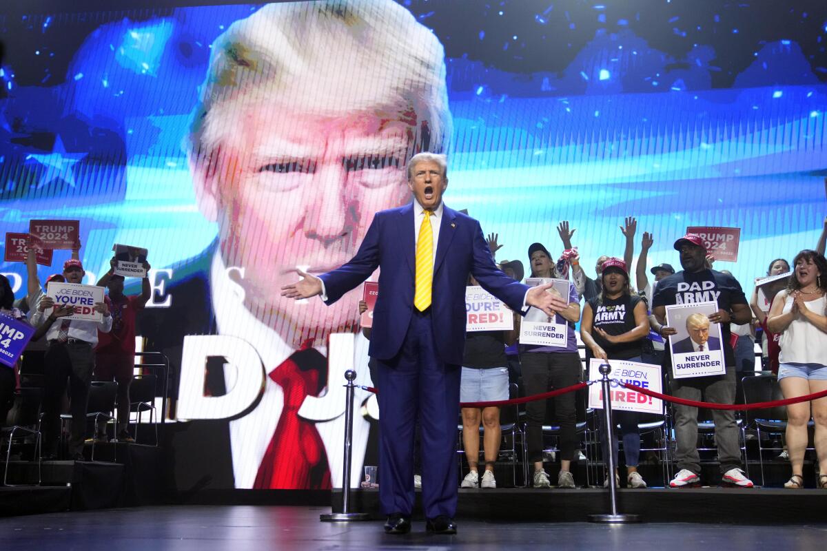Trump speaks at a campaign rally in front of a huge image of himself