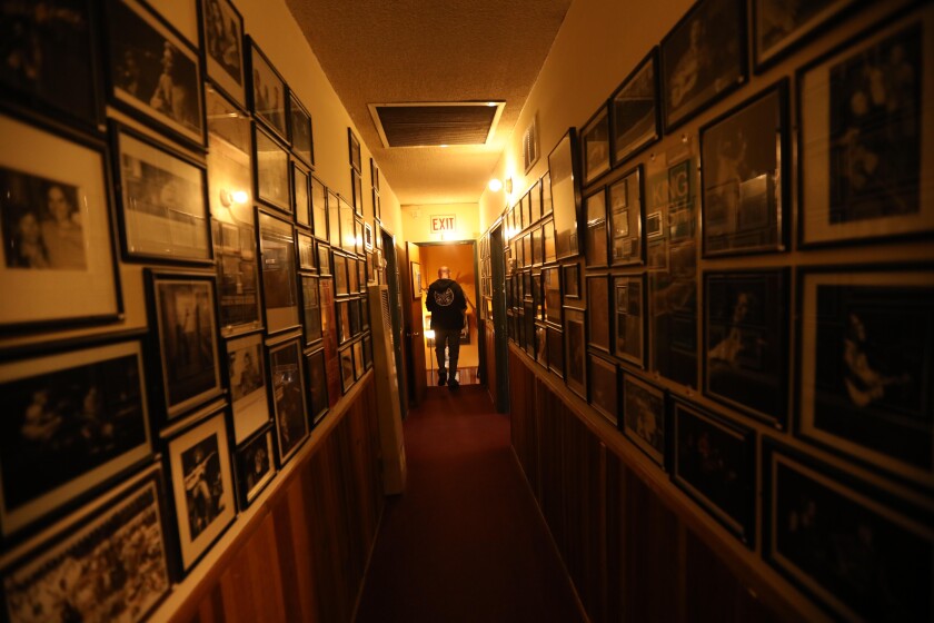 Bassist Denny Croy walks down a hallway of photographs