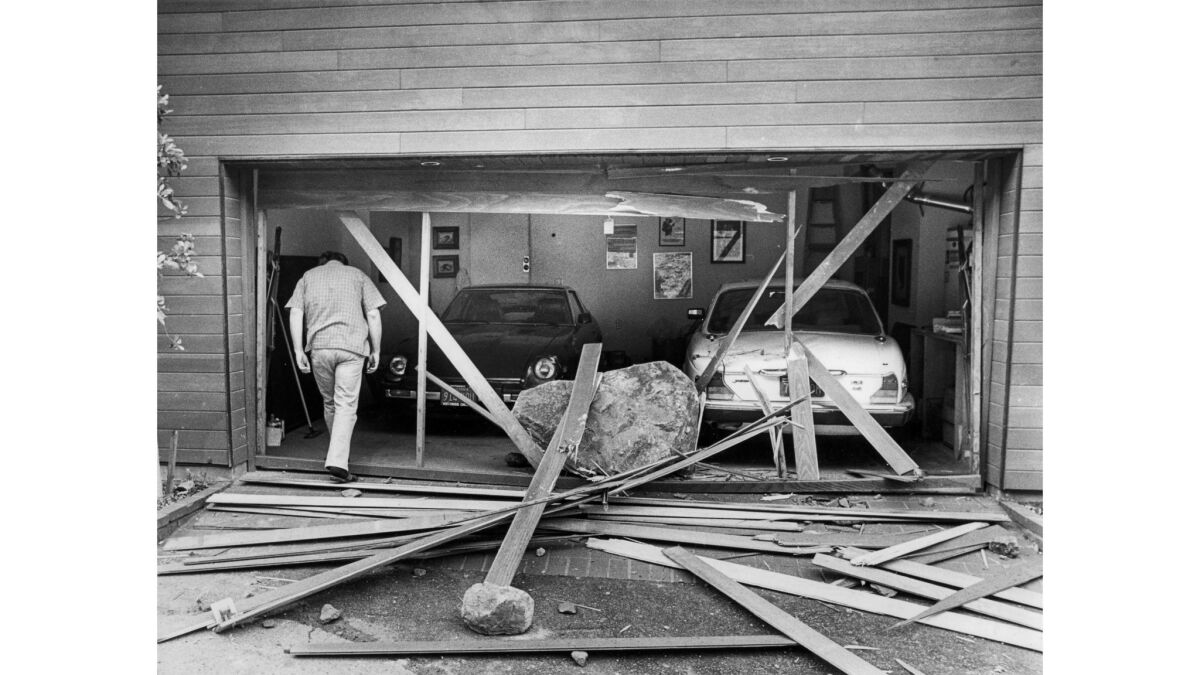 March 24, 1983: Robert Tellier, owner of a home on 19700 block of Pacific Coast Highway, enters the garage where a boulder crashed through the door, damaging both cars.