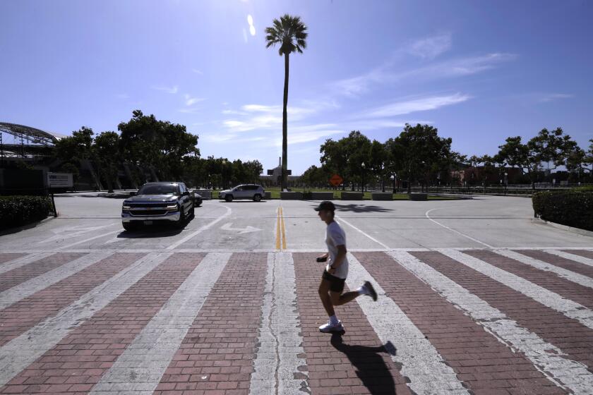A man runs along Figueroa Street by the front entrance to Exposition Park In Los Angeles on May 9, 2022.