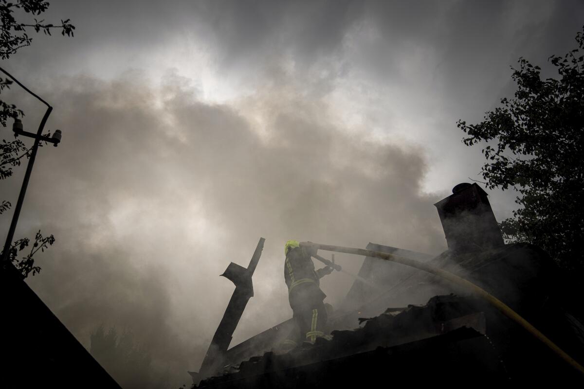 A rescue worker puts out the fire on a destroyed house after a Russian attack in a neighborhood in downtown Kharkiv Monday.