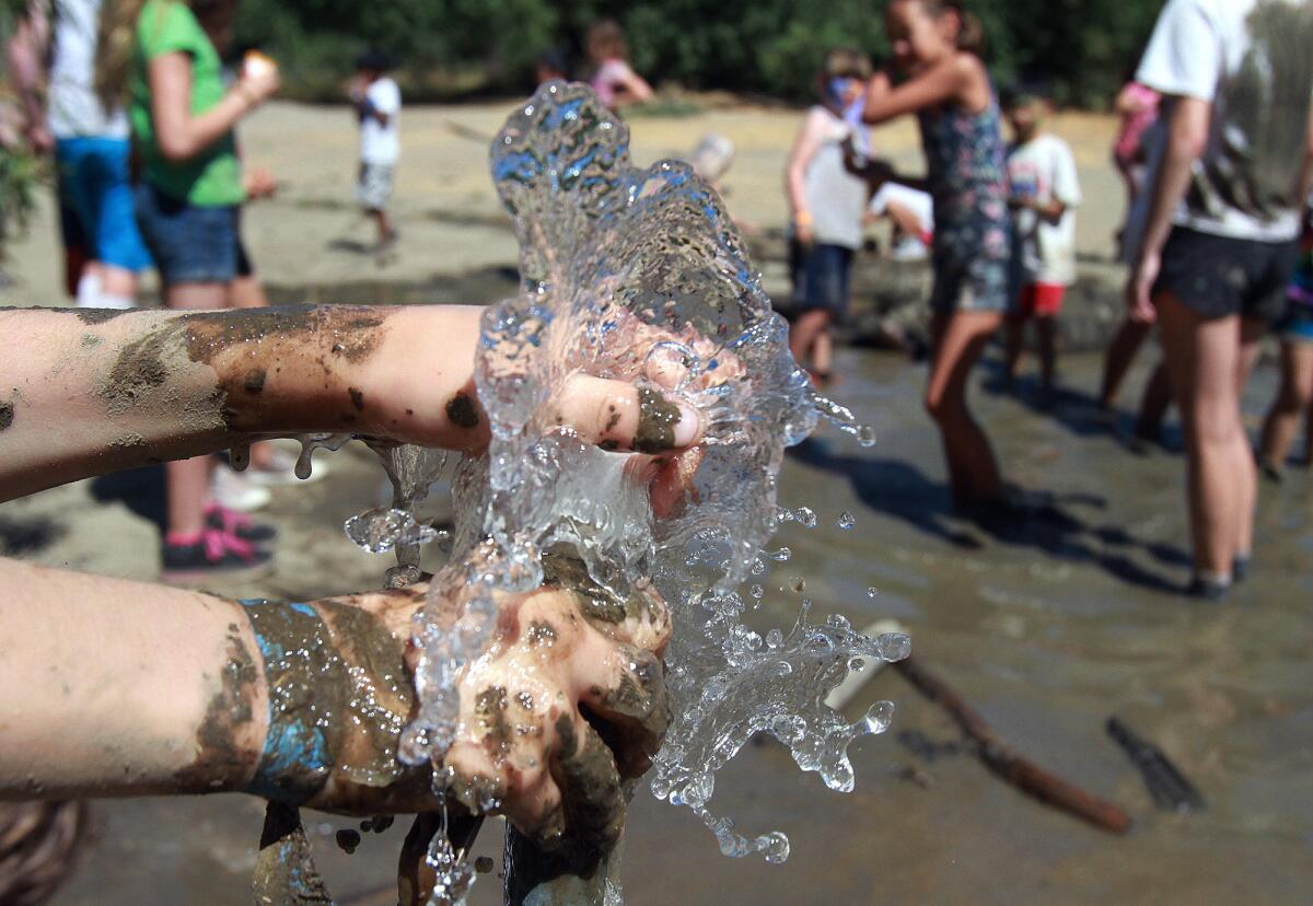 A pipe slowly gurgles water that a Tom Saywer Camp camper uses to rinse mud off her hands during MUD time in La Canada Flintridge on Tuesday, August 5, 2014.