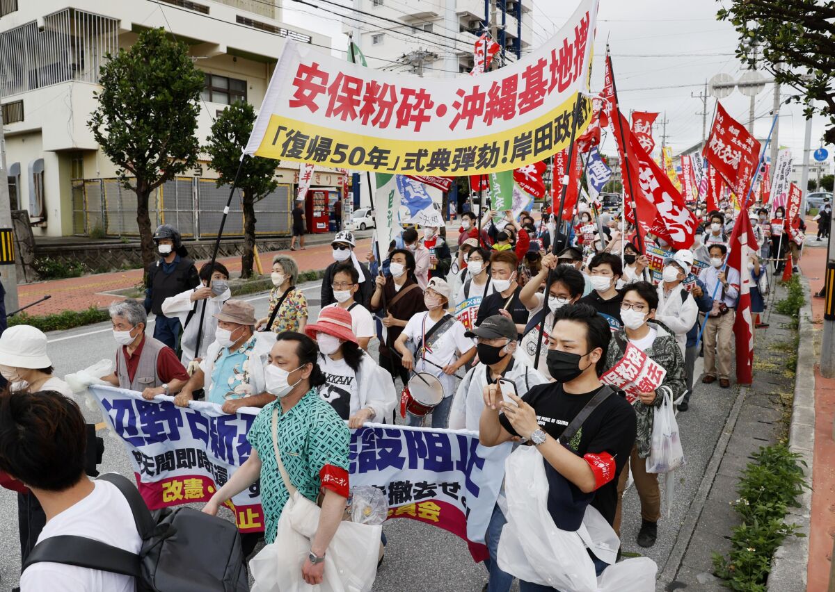 Protesters march, opposing to the ceremony marking the 50th anniversary of its return to Japan after 27 years of American rule on May 15, 1972, in Ginowan, Okinawa, Sunday, May 15, 2022. Protesters staged a rally demanding a speedier reduction of U.S. military forces.(Kyodo News via AP)