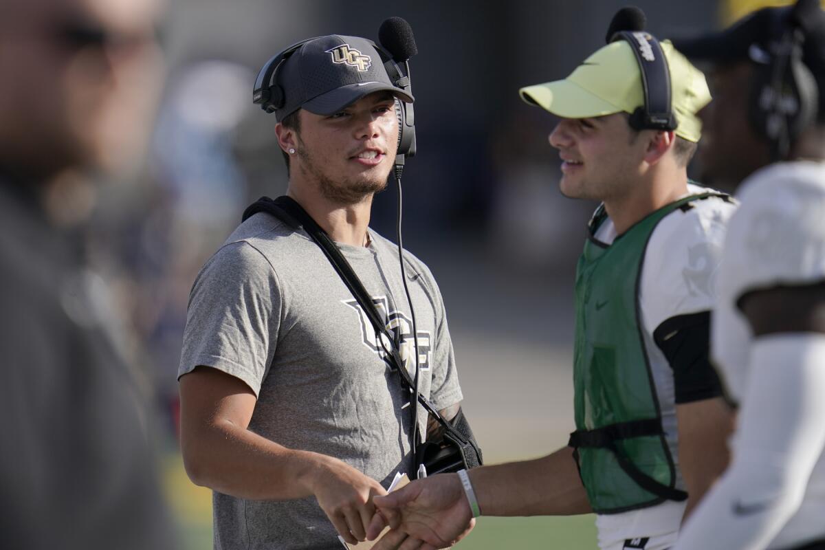 UCF quarterback Dillon Gabriel wears a sling while walking on the sidelines.